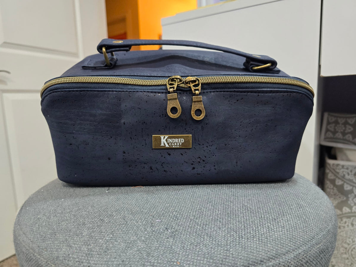 Charles Dopp Kit in navy cork with antique brass hardware, straight-on front view