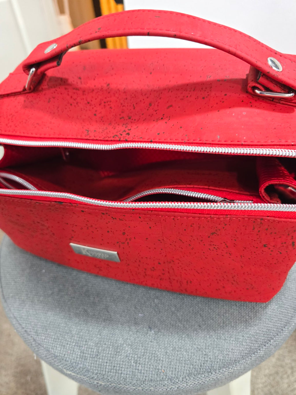Red cork Charles Dopp Kit handle, silver hardware, and main zipper detail