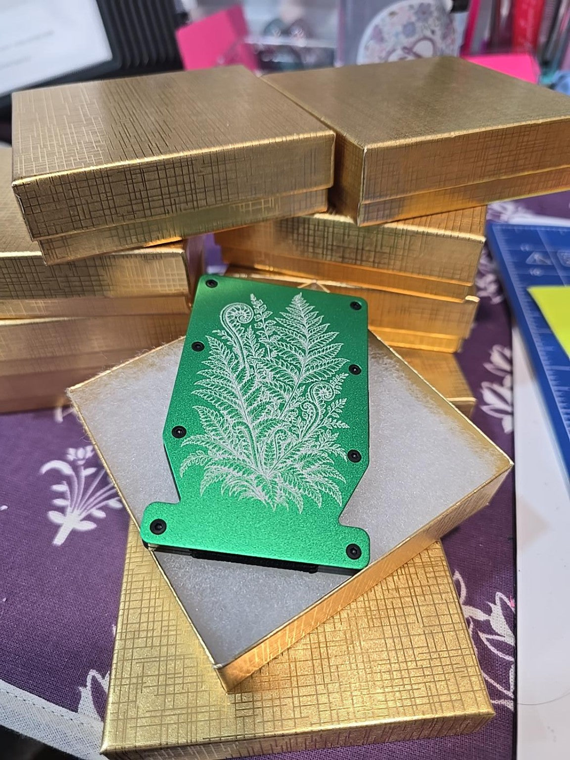 Grass green metal Notch RFID wallet engraved with silver fern fronds and fiddleheads, presented in a gold gift box